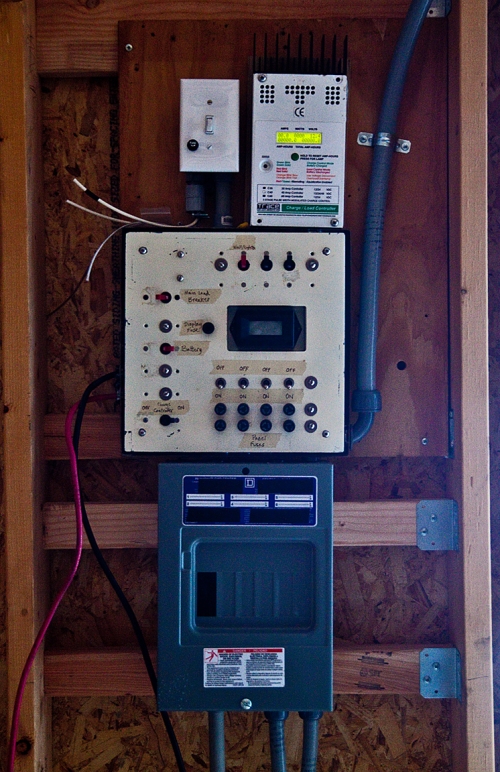 A close-up of the power controls. On the top right is the charge controller. Next to it is the switch for the lighting (not yet installed). Below them is the breaker box, and on the bottom is the box housing three 12v voltage regulators. One for the wall outlets, and one for each pier outlet.